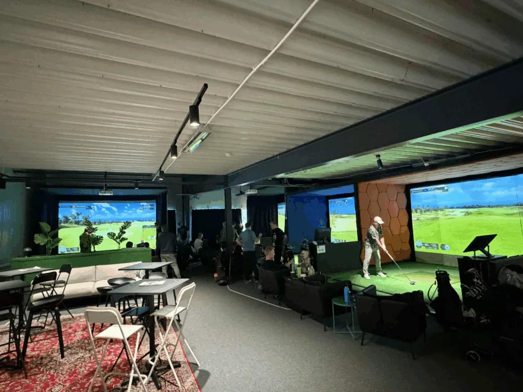 BA Golfs simulatorhall med golfskärmar och sittplatser.